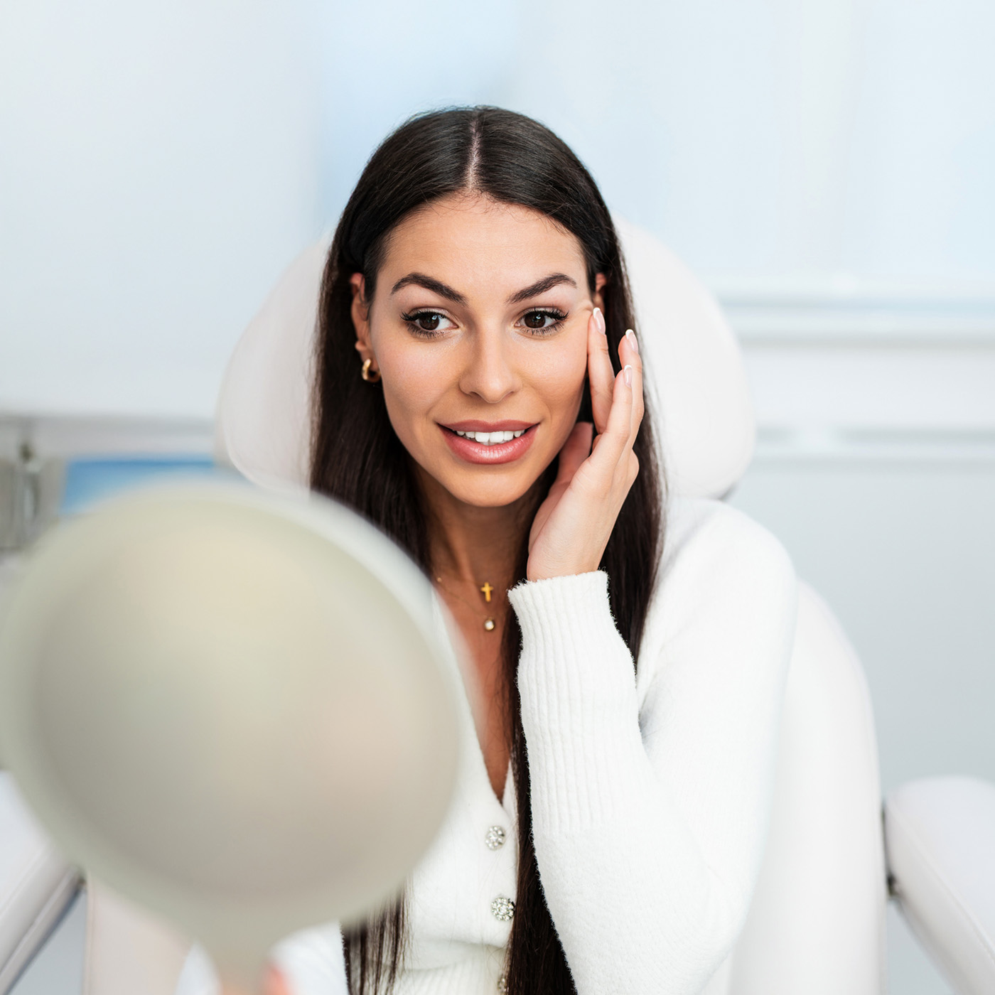 Braunhaarige Frau schaut ihre Ergebnisse nach einer Behandlung im Spiegel an